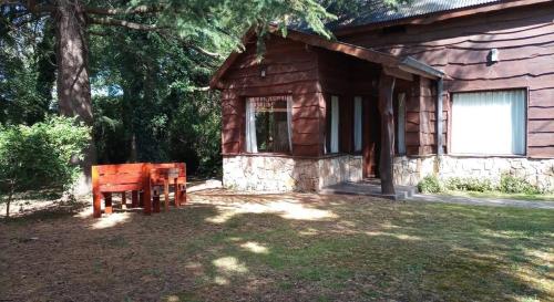a log cabin with a bench in front of it at Cabaña de los Tres Pinos in Sierra de los Padres