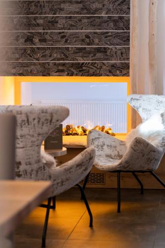 two chairs sitting in front of a table with a fireplace at Ursprung Panorama Hotel Königsleiten in Königsleiten