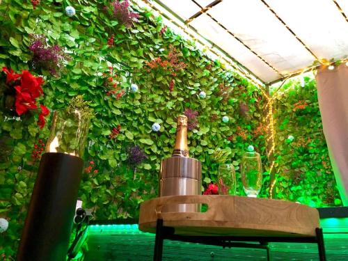 a green wall with flowers and a bottle of wine at La lover’s jungle in Pont-sur-Yonne