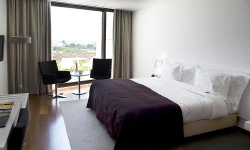 ein Hotelzimmer mit einem Bett und einem großen Fenster in der Unterkunft Pousada Palacio de Estoi – Small Luxury Hotels of the World in Estói