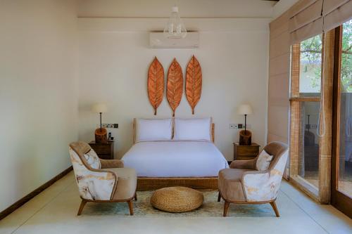um quarto com uma cama e 2 cadeiras em O2 Villas Yala em Yala