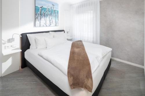 ein Schlafzimmer mit einem weißen Bett mit einer braunen Krawatte darauf in der Unterkunft Damenpfadpalais in Norderney