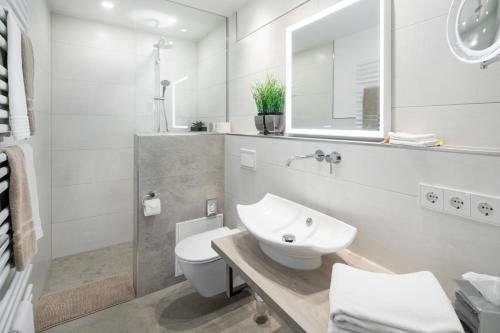ein weißes Bad mit einem Waschbecken und einem WC in der Unterkunft Damenpfadpalais in Norderney