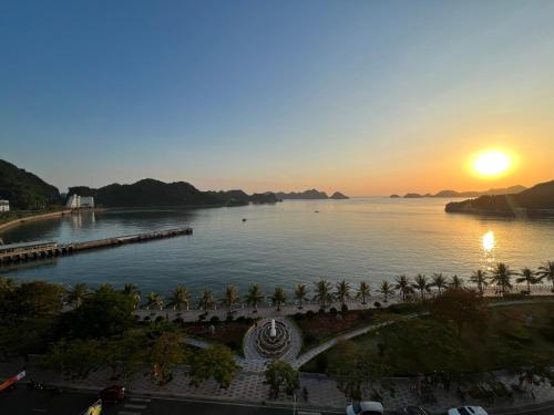 Huong Cang Sea View Hotel في كات با: غروب الشمس على جزء من الماء مع أشجار النخيل