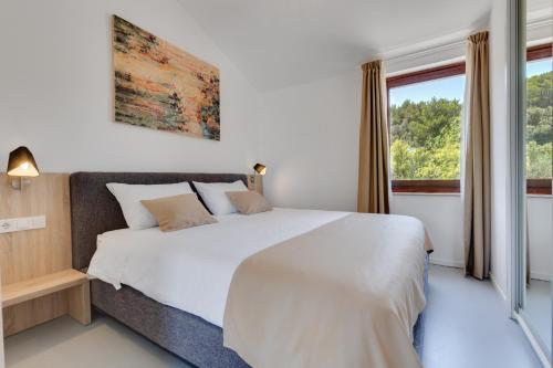 a bedroom with a large white bed and a window at Apartments Jezera Lovišća in Jezera