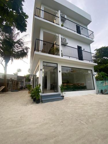 a white building with a balcony and a patio at kunaa beach Inn in Fulidhoo