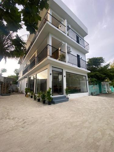 a large white building with a balcony and potted plants at kunaa beach Inn in Fulidhoo