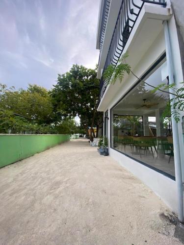 a building with a walkway next to a green wall at kunaa beach Inn in Fulidhoo