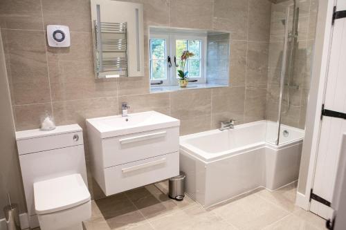 a bathroom with a sink and a toilet and a bath tub at Calcot Farmhouse in Chirbury