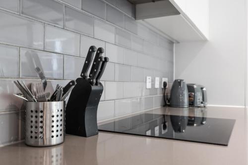 a kitchen with a counter with utensils in a container at Cave Apartments in London