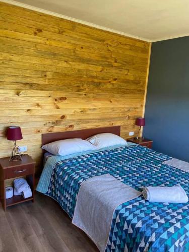 ein Schlafzimmer mit einem Bett und einer Holzwand in der Unterkunft Cabañas del Llano in Puyehue