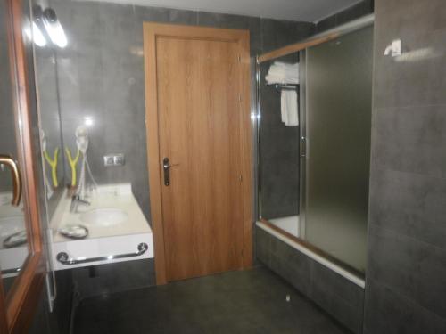 a bathroom with a sink and a wooden door at Hotel Victor in Rialp