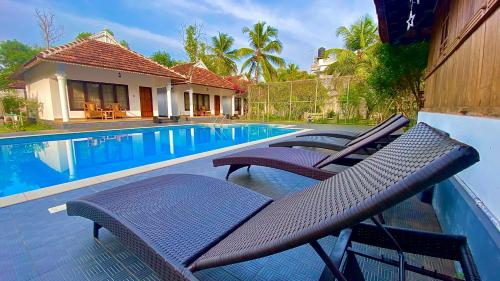 a couple of chairs sitting next to a swimming pool at Marari Green Villas in Mararikulam