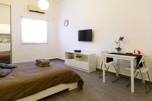 Schlafzimmer mit einem Bett, einem Schreibtisch und einem TV in der Unterkunft Romantic Studio Diz Frishman in Tel Aviv