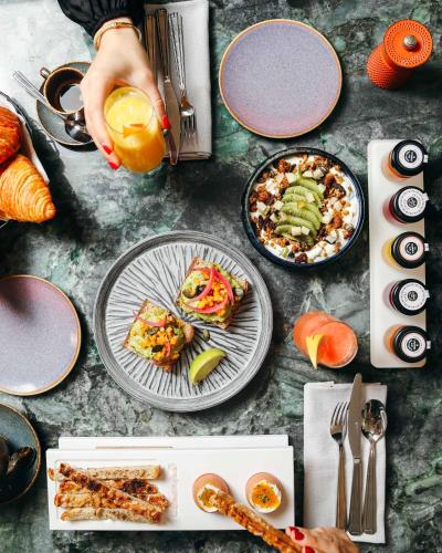 a table with plates of food and a person holding an orange at Kimpton - St Honoré Paris by IHG in Paris