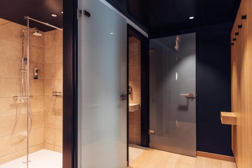 ein Bad mit einer Dusche und einer Glastür in der Unterkunft harry's home Bern-Expo in Bern