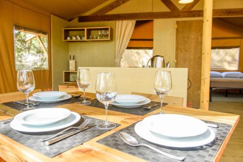 a table with plates and wine glasses on it at Camping Maremma Sans Souci in Castiglione della Pescaia