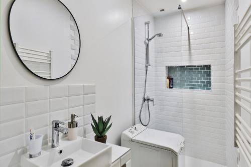 Baño blanco con lavabo y espejo en Appartement Le Cocon Lyonnais, en Villeurbanne