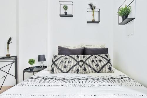 Dormitorio blanco con cama y plantas en la pared en Appartement Le Cocon Lyonnais, en Villeurbanne