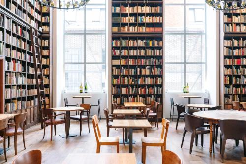 a library with tables and chairs and bookshelves at B2 Hotel Zürich in Zürich