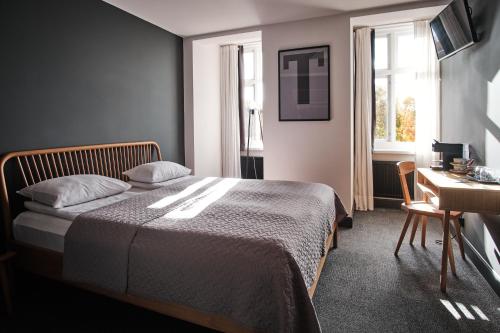 a bedroom with a bed and a desk and window at Vanadziņa māja in Cēsis