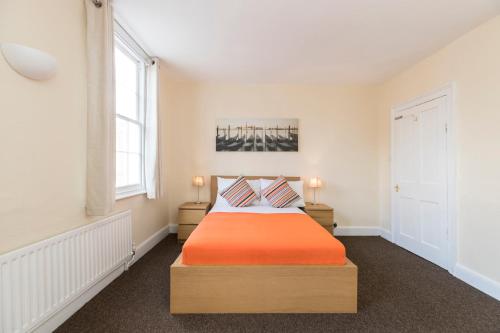 ein Schlafzimmer mit einem Bett mit einer orangefarbenen Decke in der Unterkunft Camden Town apartments in London