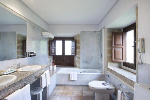 a bathroom with two sinks and a tub and a toilet at Parador de Cangas de Onís in Villanueva de Cangas de Onís