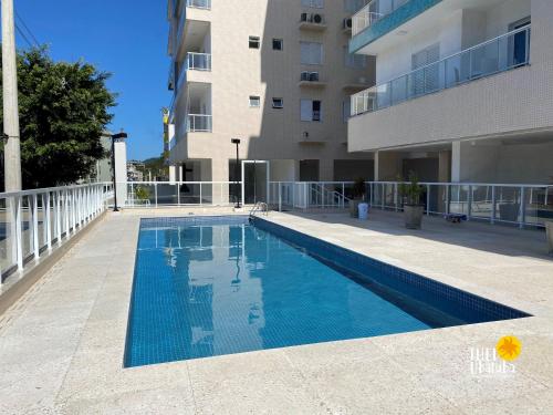 a swimming pool in front of a building at Espaçoso, bem equipado AR e piscina Climatizada in Ubatuba