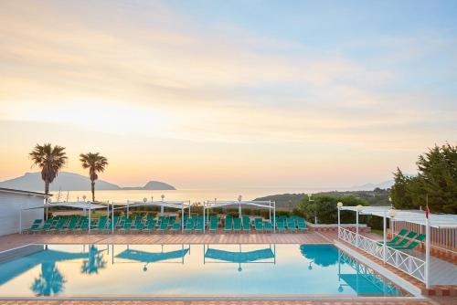 a pool with chairs and the ocean in the background at Hotel Baia Aranzos in Pittulongu