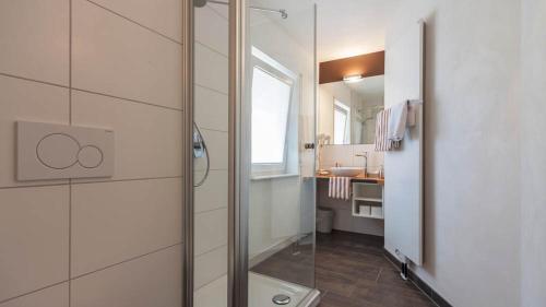 a bathroom with a shower with a sink and a mirror at Landhaus Müller in Immenstaad am Bodensee