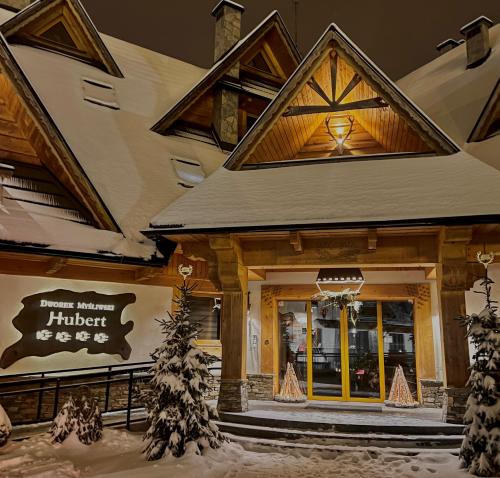 a store front of a building with snow on the ground at Dworek Myśliwski Hubert-świetna lokalizacja 50m od Term Bania ,100m od wyciągu Kotelnica in Białka Tatrzańska