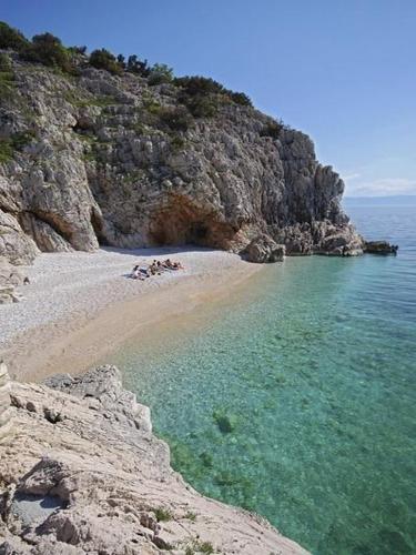 a group of people laying on a beach near the water at Apartments Barbara in Brseč
