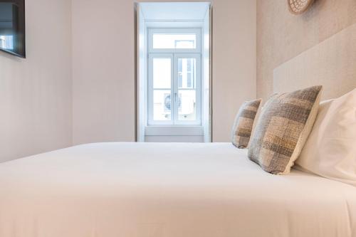 a white bed with two pillows and a window at Ando Living - Douradores House in Lisbon
