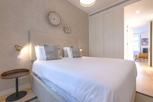a bedroom with a large white bed and a table at Ando Living - Douradores House in Lisbon