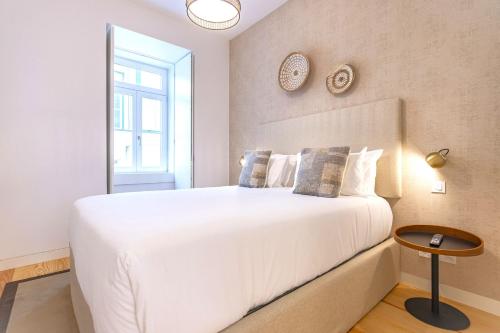 Un dormitorio con una gran cama blanca y una ventana en Ando Living - Douradores Townhouse en Lisboa