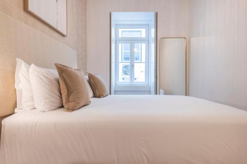 a bed with white sheets and pillows in a room at Ando Living - Douradores House in Lisbon
