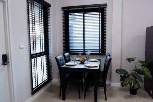 a dining room with a table and chairs and windows at LARGE & QUIET 3bd Home with Security & Pool in Ubon Ratchathani