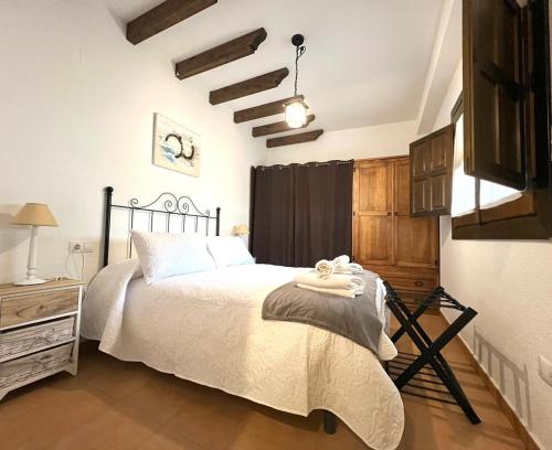 a bedroom with a bed with white sheets and a chandelier at tuGuest Carataunas Apartment Alpujarra V in Carataunas