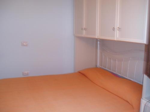 a bedroom with an orange bed and white cabinets at Il Girasole in SantʼAntìoco