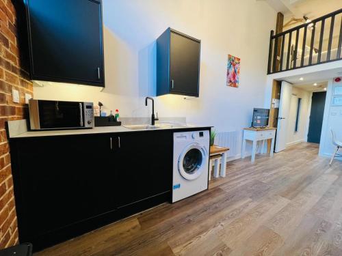 a kitchen with a washing machine and a microwave at Apartment 5 Sullivan House in Hereford