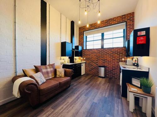 ein Wohnzimmer mit Sofa und Ziegelwand in der Unterkunft Apartment 5 Sullivan House in Hereford