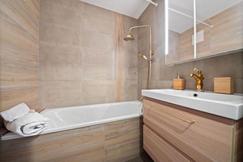 ein Badezimmer mit einer weißen Badewanne und einem Waschbecken in der Unterkunft Charmant studio rénové situé dans les bains d'Ovronnaz, immeuble les Sources in Ovronnaz