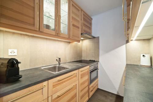 a kitchen with wooden cabinets and a sink at Charmant studio rénové situé dans les bains d'Ovronnaz, immeuble les Sources in Ovronnaz