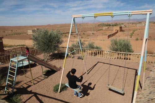 a man is playing on a swing in the desert at Taloute Ecolodge in Skoura