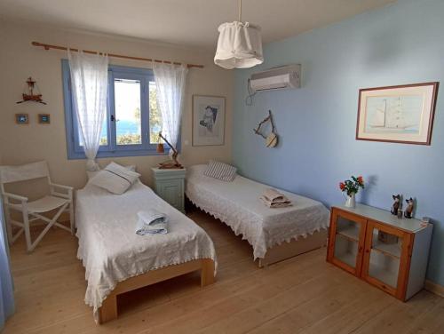 a bedroom with two beds and a table and a window at C & C _ Cycladic house with endless sea view in Ermoupoli