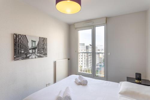 Habitación blanca con cama y ventana en Le Lounge - 2 chambres avec parking en Rennes