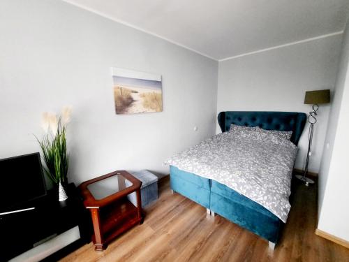 a bedroom with a blue bed and a wooden floor at Light Apartment in Rīga