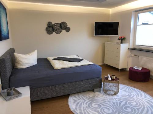 a bedroom with a bed and a tv and a table at Saarland Appartements in Wadgassen
