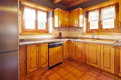 a kitchen with wooden cabinets and a sink and a dishwasher at El Jardí Secret by FeelFree Rentals in Escuñau