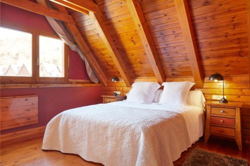 a bedroom with a white bed and a wooden ceiling at El Jardí Secret by FeelFree Rentals in Escuñau